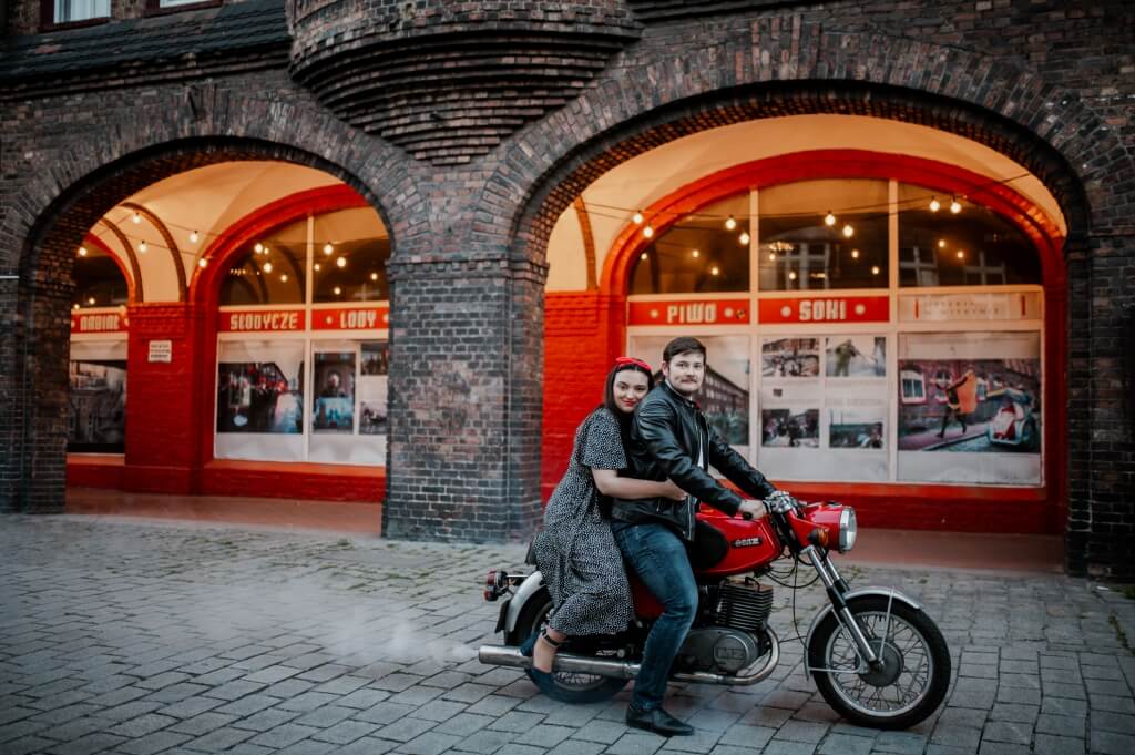 Meżczyzna klekający przed kobietą i całujacy ją w brzuszek przed porodem.